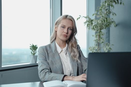 pexels-photo-5717550-5717550 Professional businesswoman at a desk in a bright office with a laptop and notebook.